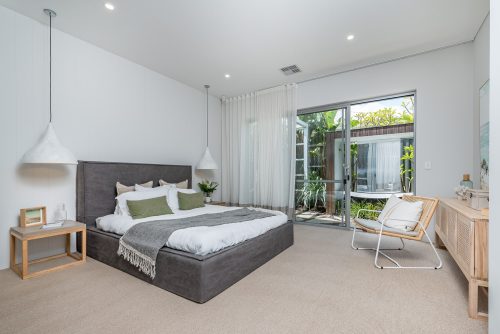 Large modern bedroom with high ceilings and oak wood furnishings.