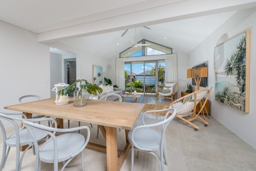 Dining and living area of home with high ceilings and neutral tones.