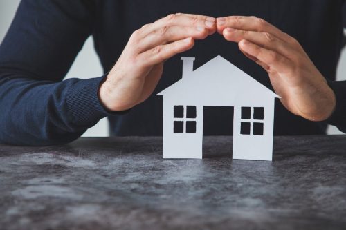 Hands covering a house, representing the question "What is landlord insurance?".